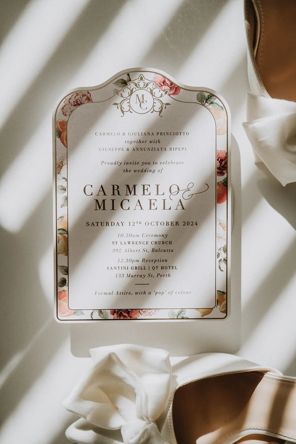 A custom die-cut wedding invitation for a Perth wedding, featuring a romantic floral border, an ornate monogram, and elegant gold foil text.