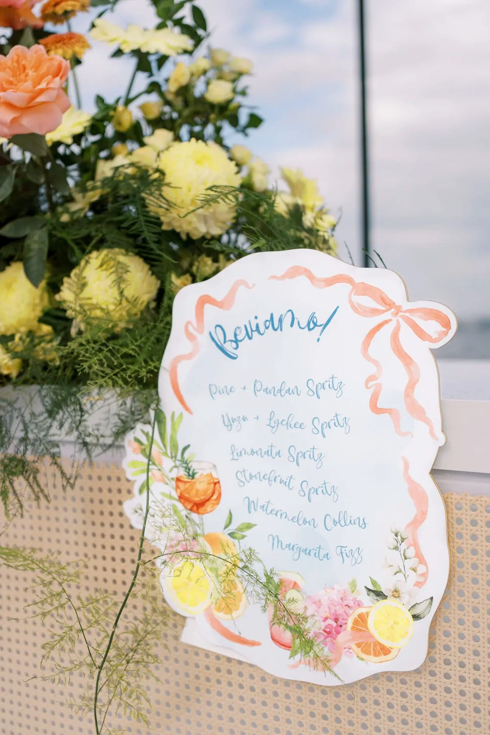 A custom-shaped wedding bar sign featuring a vibrant watercolour illustration of cocktails and a playful 'Beviamo!' heading.