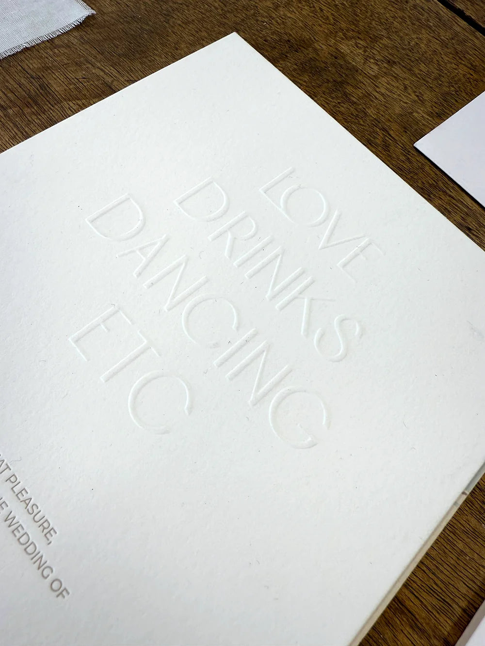 A close-up of a minimalist wedding card showcasing deep blind embossing on premium, thick 600gsm cotton paper for a luxurious tactile finish.