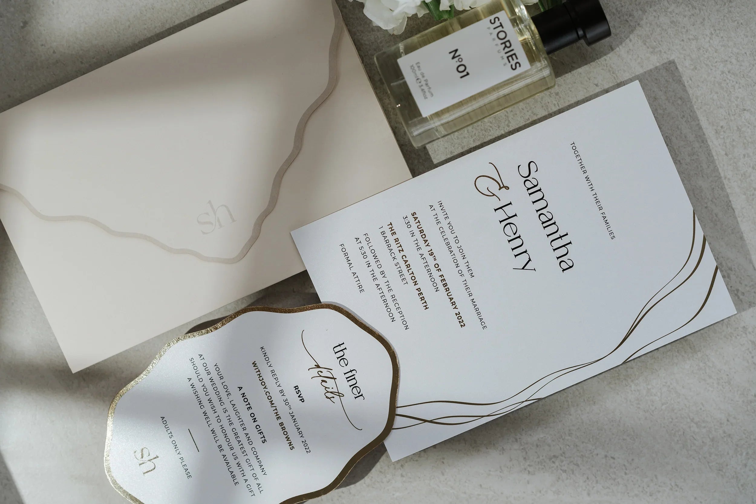 Elegant wedding invitation set with gold foil accents, envelope, and RSVP card on stone surface