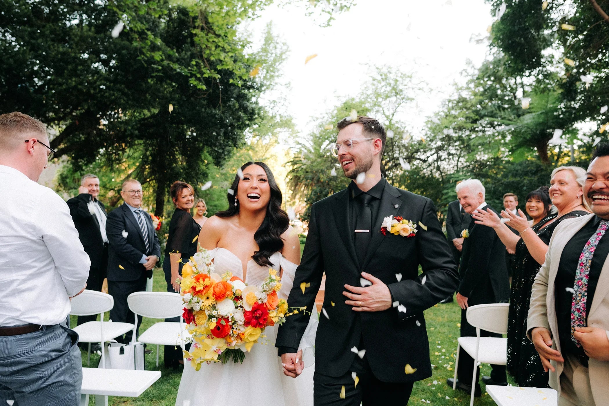 A joyful couple, clients of Felicitations, celebrate their real wedding surrounded by guests, showcasing the memorable moments our stationery helps create.