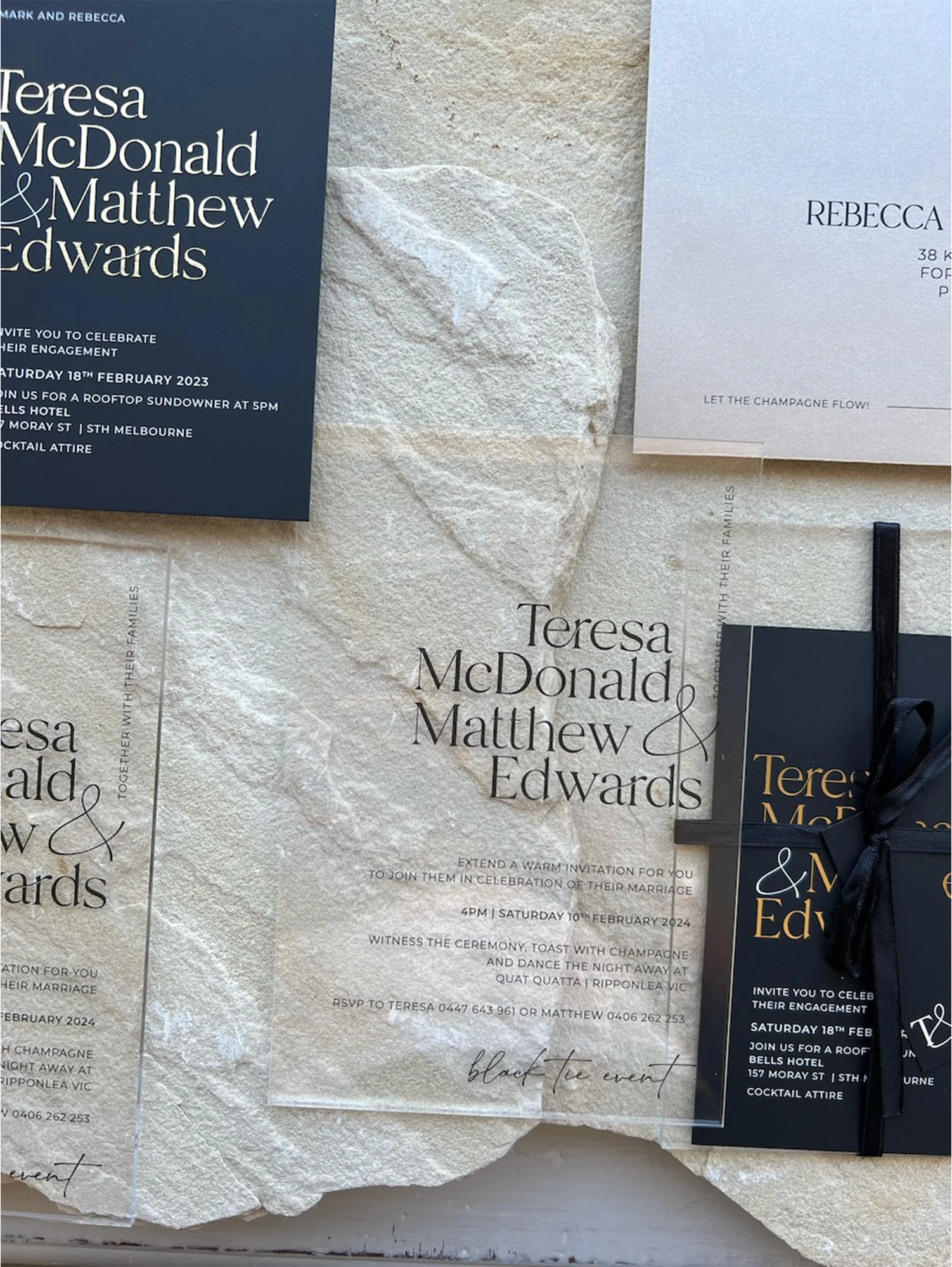 A modern wedding stationery suite showcasing a clear acrylic invitation alongside black card variations with crisp white ink and elegant gold foil.