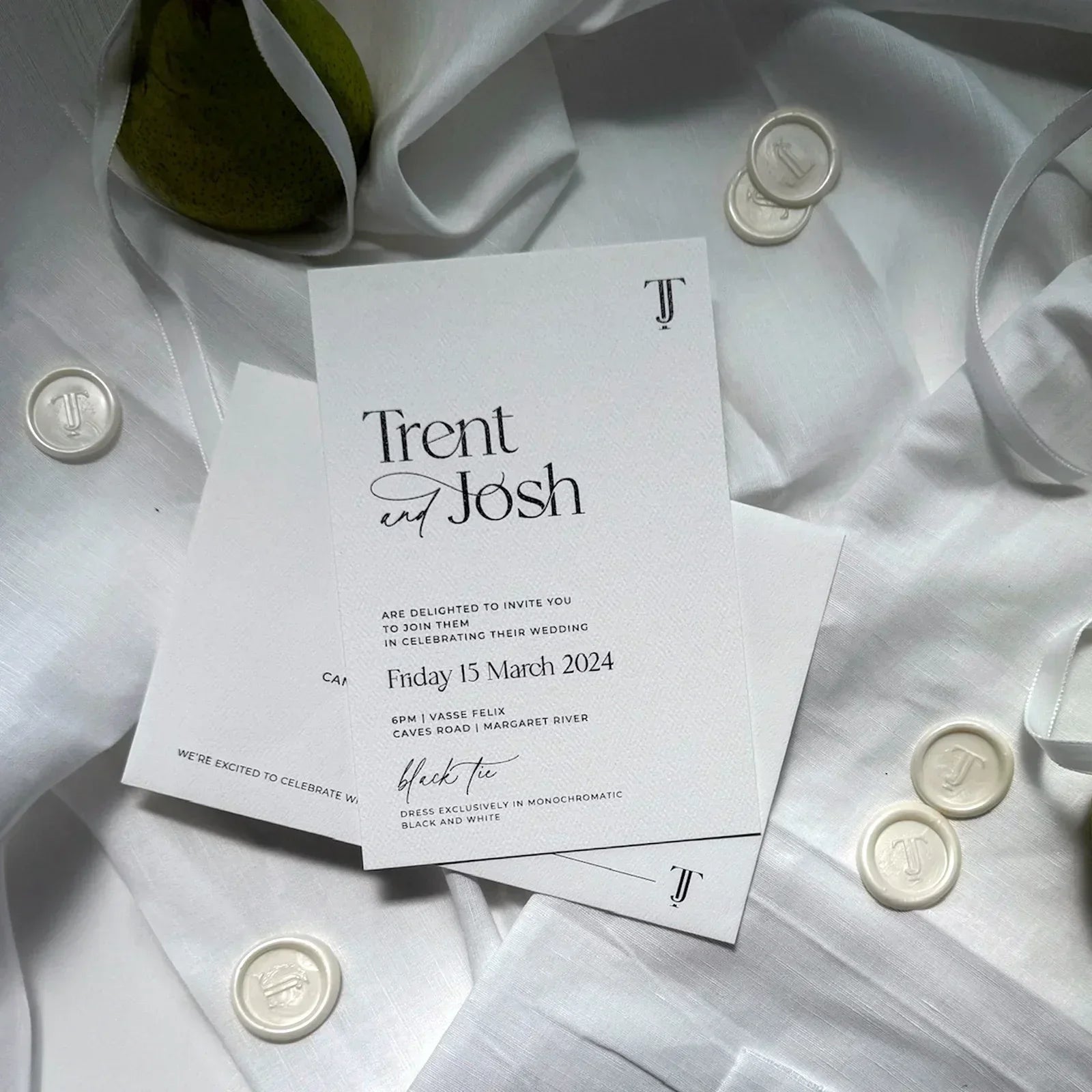 Modern wedding invitation for Trent and Josh on white fabric with wax seals and ribbon
