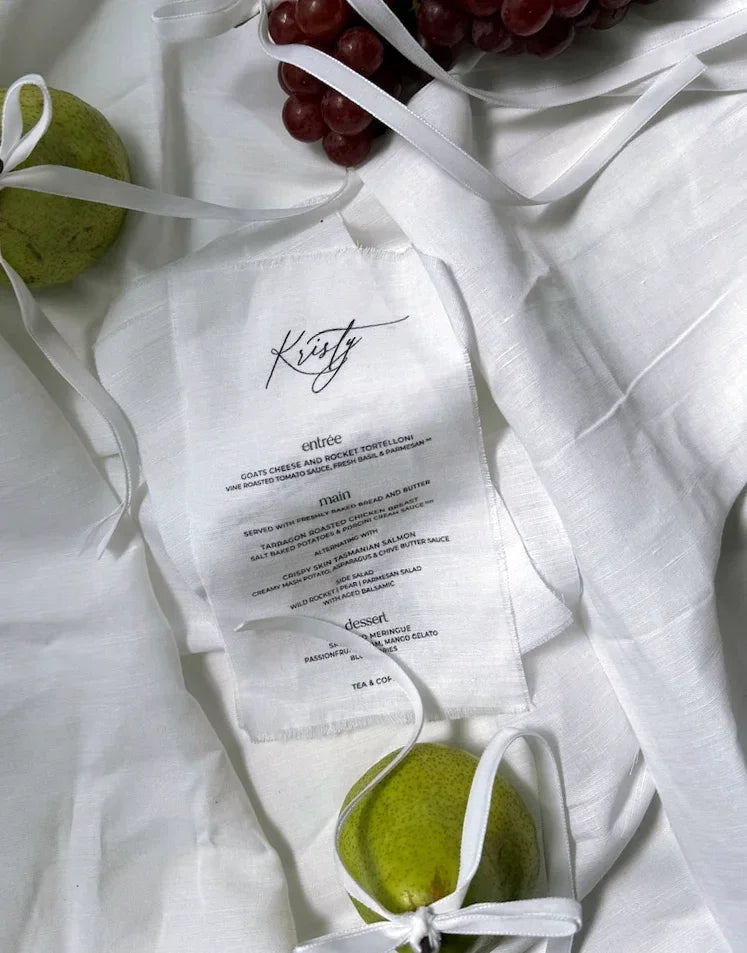Personalised white linen wedding menu with elegant script and pear and grapes decoration