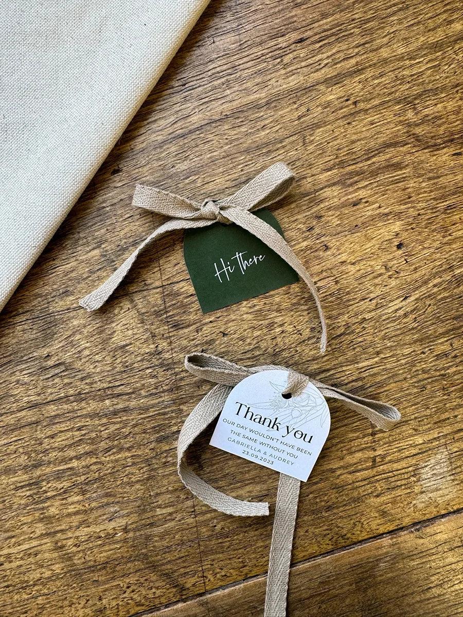 Wedding thank you and greeting tags with beige ribbon on rustic wooden table