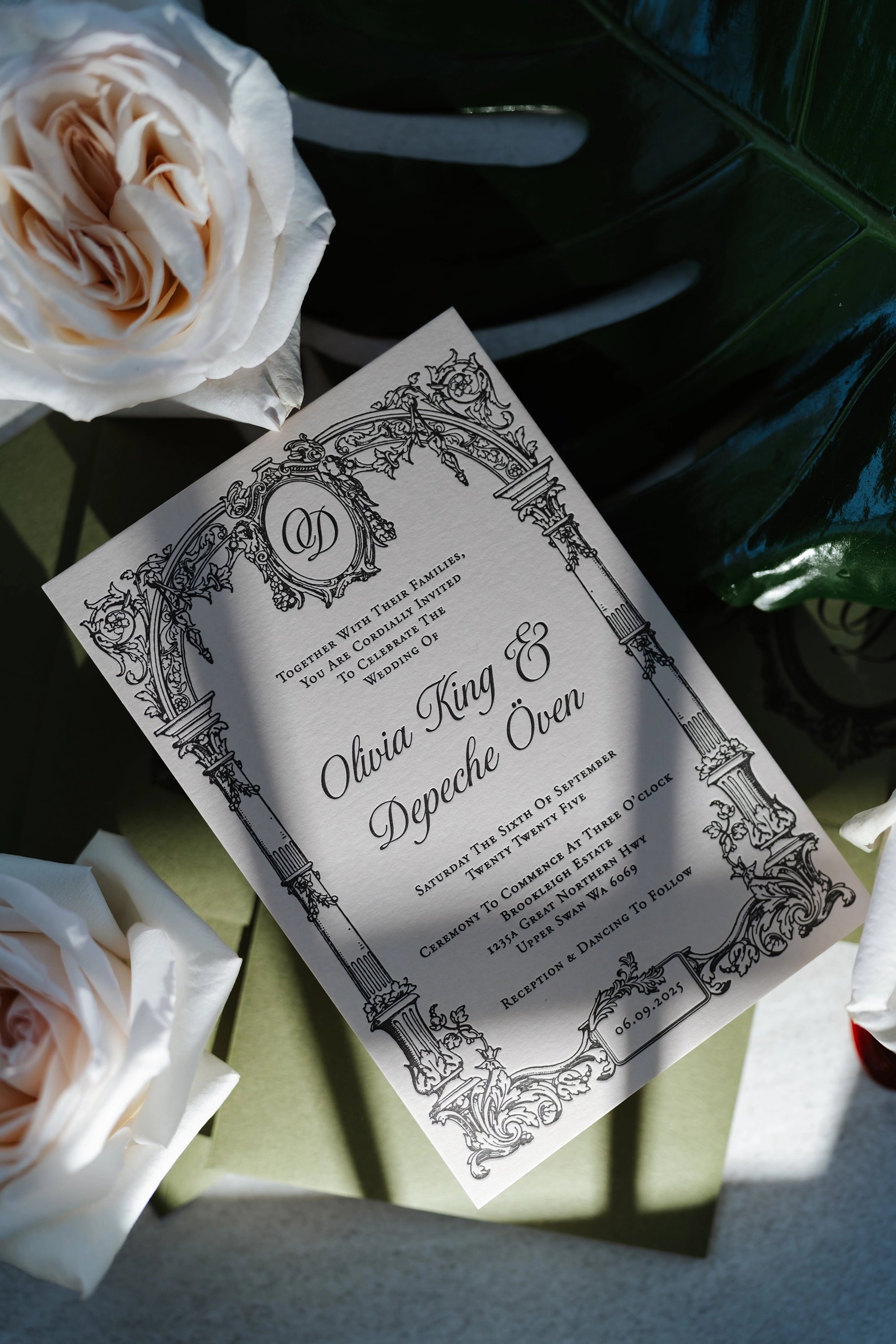 The Bordeaux Suite ornate Victorian wedding invitation for Olivia King and Depeche Oven with archway monogram surrounded by white roses and monstera by Felicitations