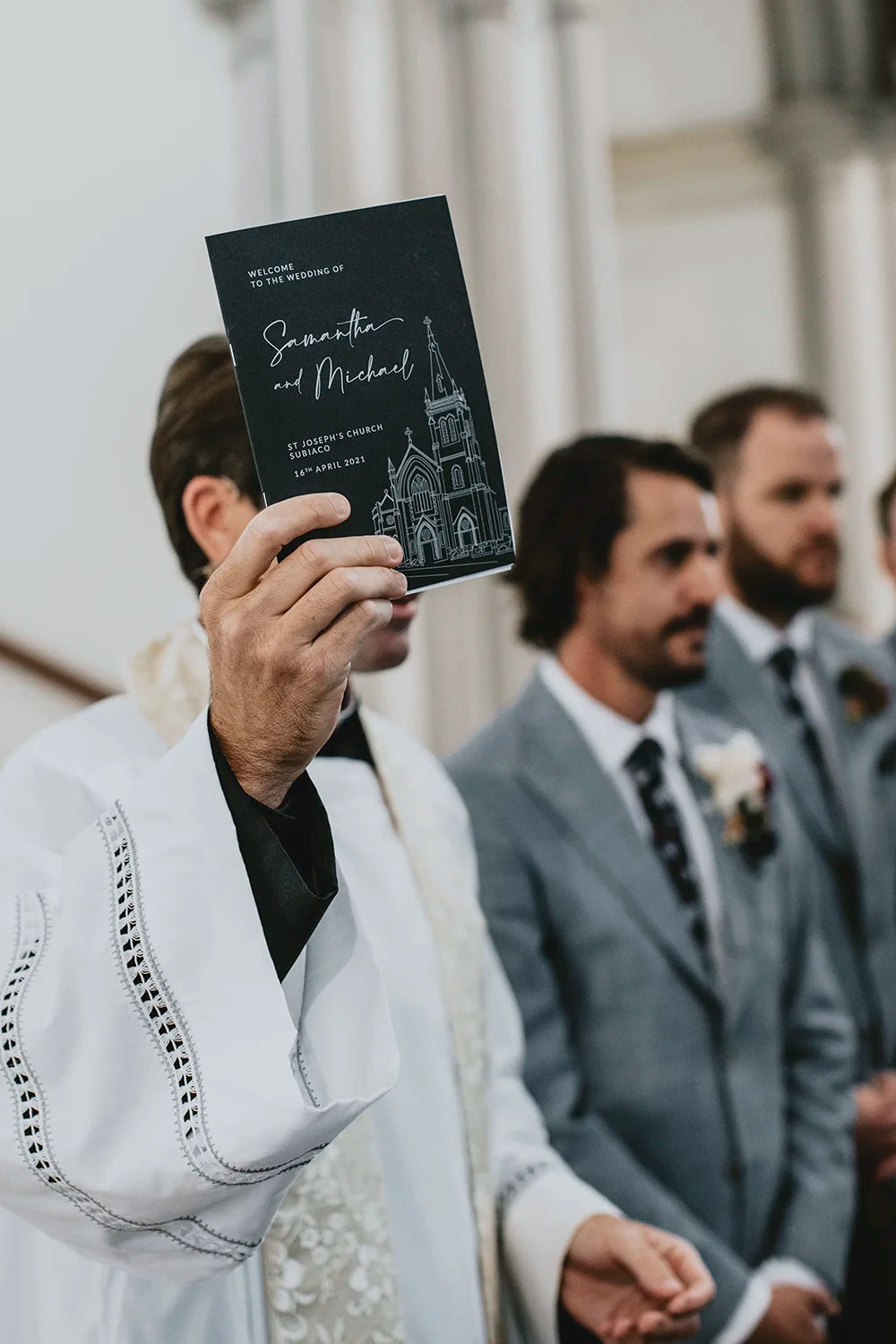 A green wedding order of service booklet featuring a custom white ink illustration of St. Joseph's Church in Subiaco, held by a priest during the ceremony.