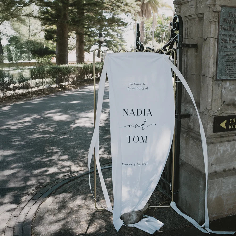 Elegant fabric wedding welcome sign for Nadia and Tom by Felicitations Perth, styled outdoors on a gold frame with romantic ribbon details.