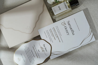 Elegant wedding invitation set with gold foil accents, envelope, and RSVP card on stone surface
