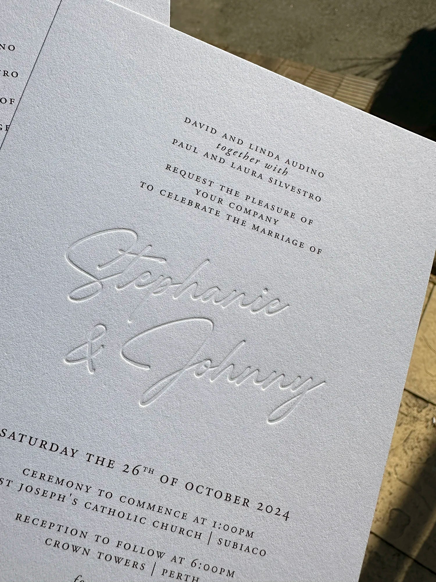 A close-up of a blind press wedding invitation for a Subiaco and Crown Towers Perth wedding, showing the elegant embossed script on thick textured card.