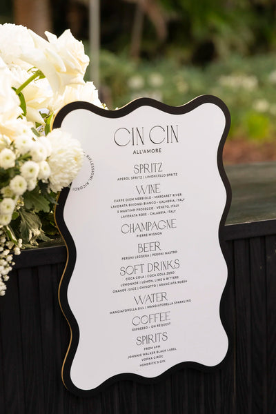 Cin Cin Allamore wavy edge wedding bar menu sign with white roses arrangement by Felicitations