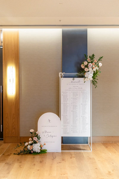 Italian wedding seating chart 'Benvenuti, il tuo posto ti aspetta' for Alexia and Calogero with arch-shaped welcome sign and blush florals