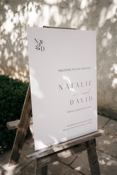 Minimalist outdoor wedding welcome sign for Natalie and David at Stones of the Yarra Valley, soft botanical monogram on wooden easel