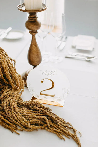 Elegant wedding table setting with gold candle holder, dried floral decor, and table number 2 sign