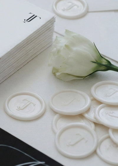 The Copenhagen Suite stack of monogrammed invitations with white wax seals featuring TJ initials and white lisianthus by Felicitations