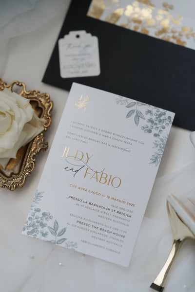 The Geneva Suite Italian wedding invitation in white with gold foil typography and dusty blue botanical illustrations for Judy and Fabio by Felicitations