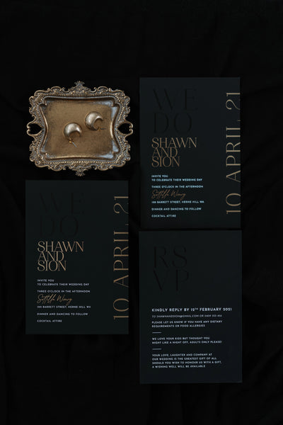 The Monaco suite flat-lay — black wedding invitation suite with rose gold foil for Shawn and Sion at Sittella Winery, with ornate brass tray and gold earrings
