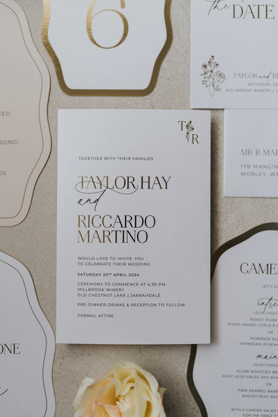 The Paris suite flat-lay with gold-edged table number 6, save the date, dinner menu and main invitation for Taylor Hay and Riccardo Martino on cream linen