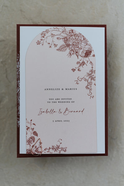 The Lisbon wedding suite — arch-shaped invitation for Isabella and Bernard with intricate burgundy floral toile illustration on blush card, matching burgundy backer