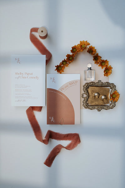 The Siena Suite wedding invitation flat lay with terracotta arch RSVP card monogrammed invitation orange dahlias velvet ribbon and vintage ring tray by Felicitations